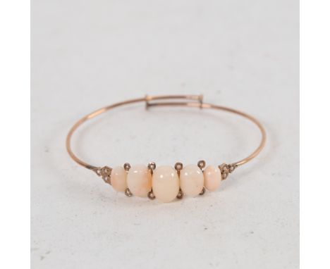 A Victorian unmarked yellow metal coral and split-pearl torque bangle/bracelet, largest internal dimensions 6cm x 5cm, 6.5g 