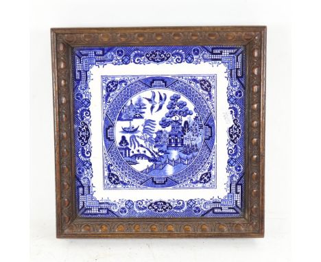 An oak-framed Willow pattern tile, 24cm across 