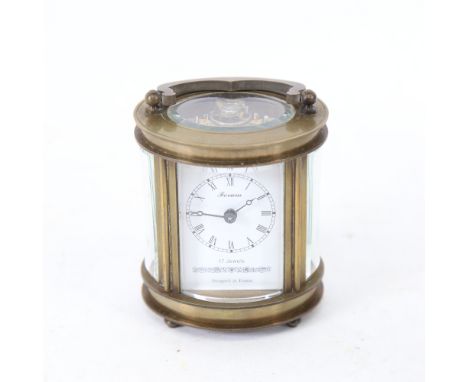 A modern Chinese oval brass-cased carriage clock, curved bevelled glass exhibition viewing plates, with swing handle, and key