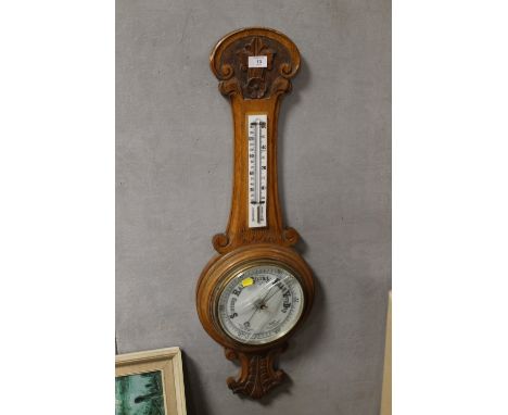 A CARVED OAK FRAMED WALL BAROMETER