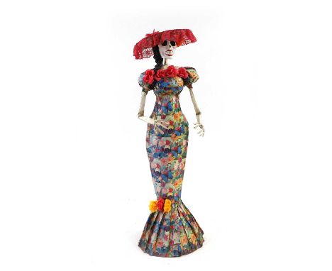 A full-size papier mache model of a female skeleton wearing a ribbon tied floral dress and tasseled hat,145cm highCondition R
