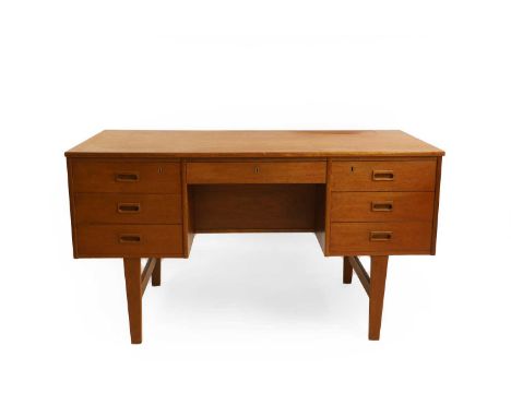 A mid-century teak desk, c.1960s, Danish, the rectangular top raised on a central drawer and two banks of three drawers, with