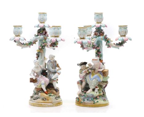 A pair of Meissen porcelain candlesticks  19th century, each modelled with a couple in 18th century dress, blue crossed sword