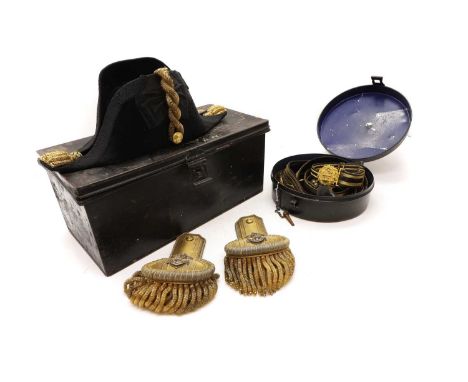 A British Royal Naval officer's bicorn hat and epaulettes, housed in a toleware case inscribed J I Baker. R.N.,the case measu