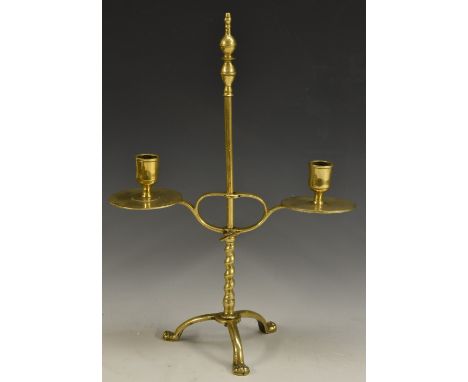 An 18th century adjustable brass tripod candlestick, quite plain, cylindrical sconces, broad disc-shaped drip pans, knot fram