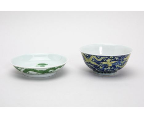 A PORCELAIN DRAGON BOWL AND DISH
A blue ground and yellow enamelled dragon bowl, with a trailing dragon amongst clouds, bears