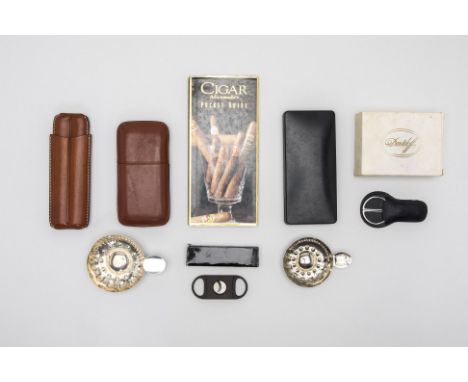 A COLLECTION OF CIGAR CUTTERS AND ACCESSORIES
To include two leather cigar cases, with one marked 'LUBINSKI' , two silver-pla