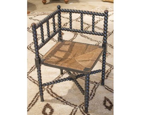 WILLIAM MORRIS STYLE CORNER CHAIR, 19th century ebonised with bobbin frame and rush seat.