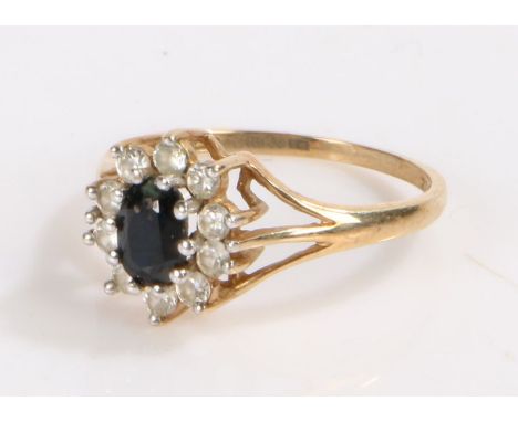 9 carat gold ring set with a central blue stone surrounded by clear paste, ring size M, 1.8g