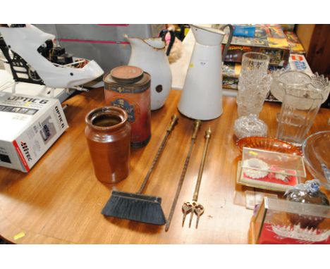 A stoneware jar, two enamel jugs, an advertising tin and fire irons 