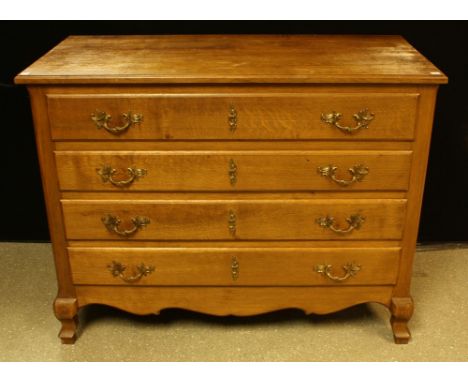 A Louis XV style oak commode, slightly oversailing rectangular top above four long drawers, brass Rococo type handles, shaped