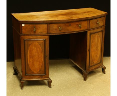 A George III mahogany sideboard, bowed rectangular top above three frieze drawers and a pair of cupboard doors, each enclosin