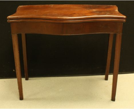 A George III mahogany serpentine card table, folding top enclosing a baize lined playing surface above a deep frieze, moulded