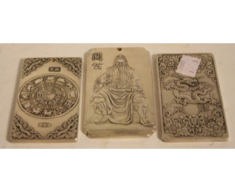 A Chinese silver ingot, cast with dragons and flaming pearl, zodiac to verso; two others, similar (3)
