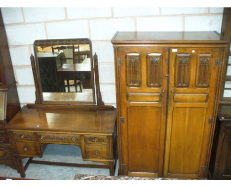 A Mid 20th Century oak gents wardrobe with carved panels and fitted interior and a conforming oak dressing table. (2)