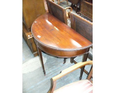 A Mahogany half moon folding games table on legs of tapering square section.