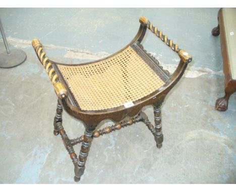 An Early 20th Century oak stool with barley twist side rails, concave rattan seat and raised on bobbin turned supports.