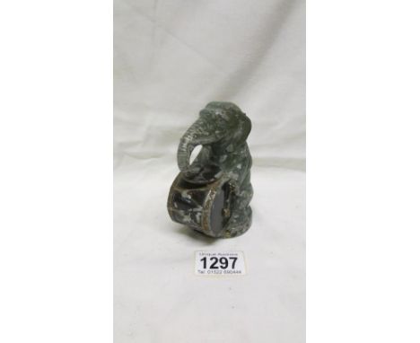 A 1920's cold painted white metal seated elephant playing a drum money bank