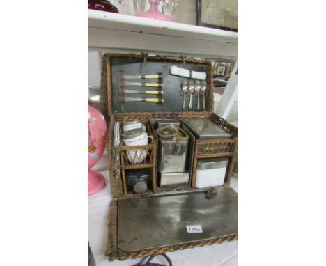 A 1920's picnic basket with enamel, china and metal containers