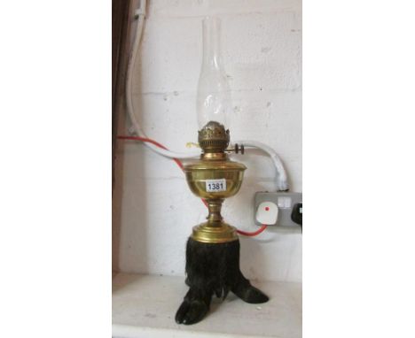 A brass oil lamp with taxidermy wild boar foot base