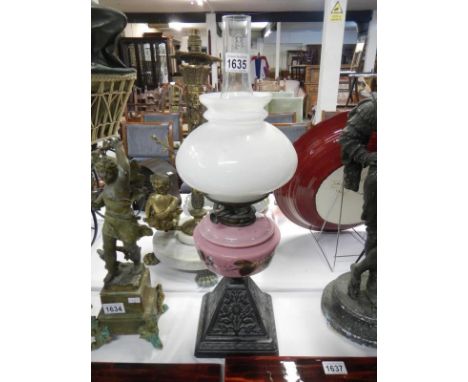 A pink glass oil lamp with shade