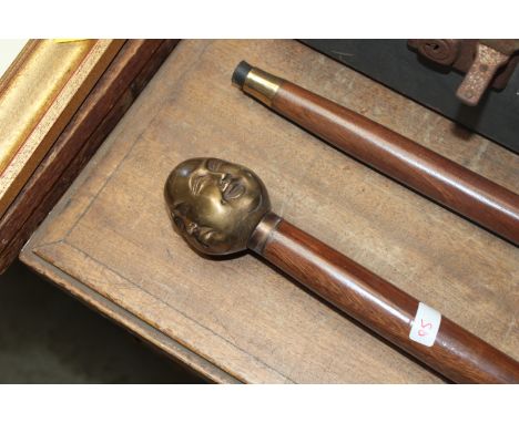 A walking stick with four faced Buddha head handle