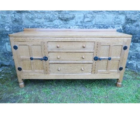 An oak sideboard, having three drawers flanked by a four panel door, to each side, below an adzed top, by Robert Mouseman Tho