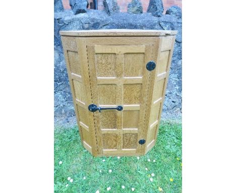 An oak panelled corner cupboard, by Robert Mouseman Thompson of Kilburn, with canted corners, width 28ins x height 38.25ins x
