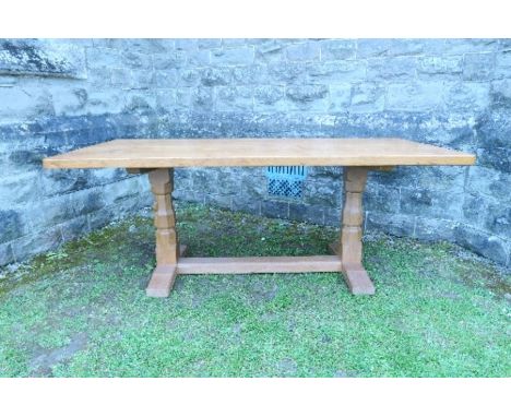 An oak rectangular adzed top dining table, raised on octagonal shaped baluster columns, with outswept feet, and united by str