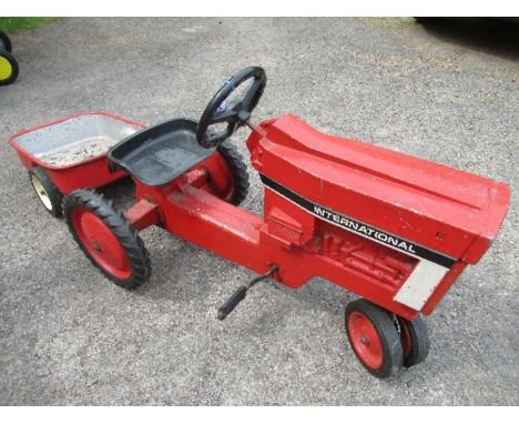 A rotary pedal&nbsp; “International” tractor and trailer, with solid rubber tyres, Tractor approx. 36” x 18”, Trailer 28” x 1