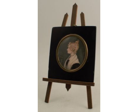 A 19th century miniature portrait of a girl, painted in profile wearing a white bonnet, with a miniature easel