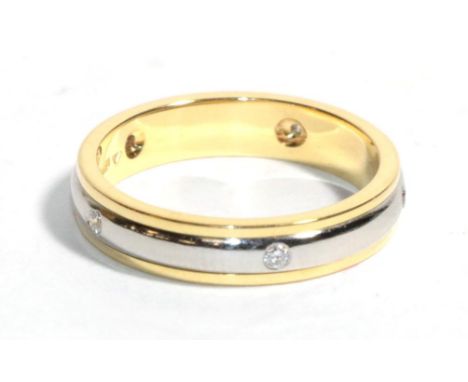 An 18 carat two colour gold diamond band ring, a white gold band inset with five round brilliant cut diamonds, between two ye