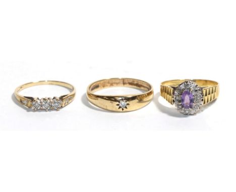 A 9 carat gold diamond solitaire ring, finger size T; a 9 carat gold three stone ring, finger size P; and an 18 carat gold am