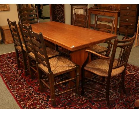 A pine kitchen table, together with a set of six rush seated ladder back dining chairs, a rush seated elbow chair, a mahogany