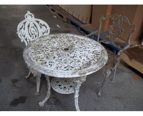 A CAST IRON GARDEN TABLE AND CHAIR WITH A MATCHED EXTRA CHAIR