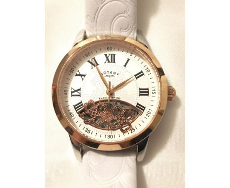 A boxed ladies Rotary automata skeleton wristwatch with Roman and Arabic numerals, gold tone bezel and white leather strap.