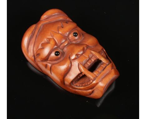 A carved boxwood netsuke formed as a mask. Length 5.5cm.  