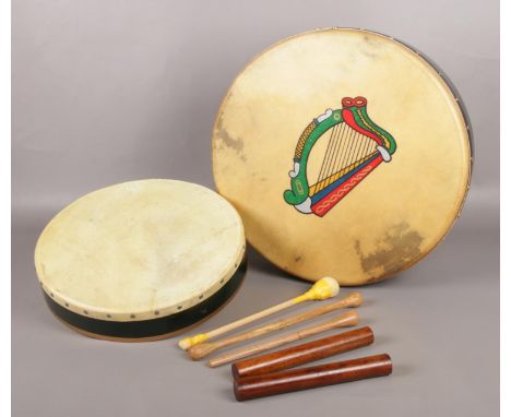 A pair of Bodhran drums, one decorated with a harp, both with protective cases.  