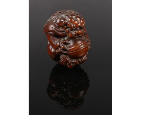 An extensively carved boxwood netsuke, formed as  temple lion holding a ball. Length 6cm.  