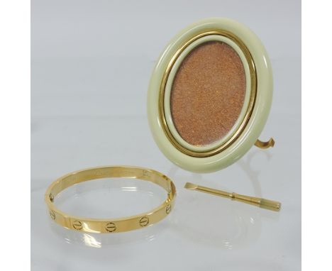 A Les Must de Cartier oval photograph frame, 9cm tall, cased, together with a plated bangle