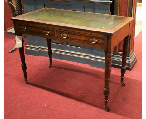 An Edwardian walnut and gilt tooled green leather inset two drawer writing table, raised on ring turned supports to castors, 