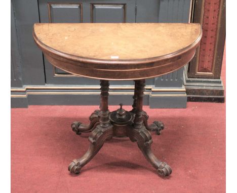 A mid-Victorian figured walnut demi-lune fold-over card table, having a baize lined interior, raised on ring turned supports 