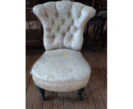 A cream upholstered button back bedroom chair, on four wooden legs. 