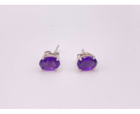 A pair of silver and amethyst stud earrings, set with oval-cut amethysts. 