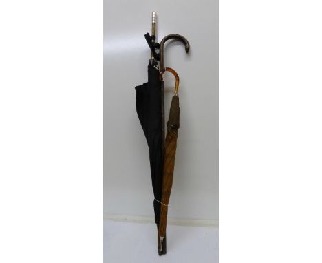 A silver banded walking stick and two umbrellas