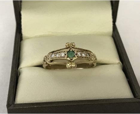 A vintage 9ct gold dress ring set with an emerald and diamonds. Decorative band style mount with central round cut emerald an