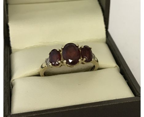 A 9ct gold garnet and diamond dress ring. Trilogy of oval cut garnets with 2 small diamonds set to each shoulder. Size Q½. To