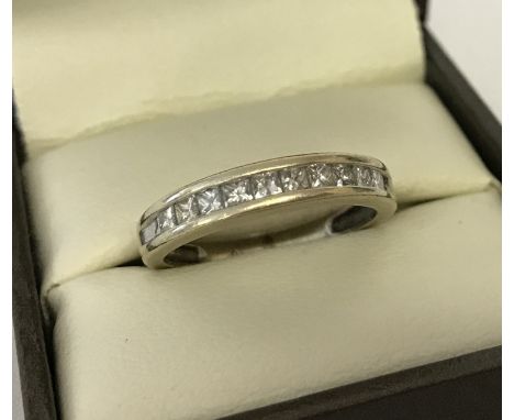 A gold channel set diamond half eternity ring. 10 square cut diamonds approx. 0.5ct. Very worn hallmarks to inside of band. T