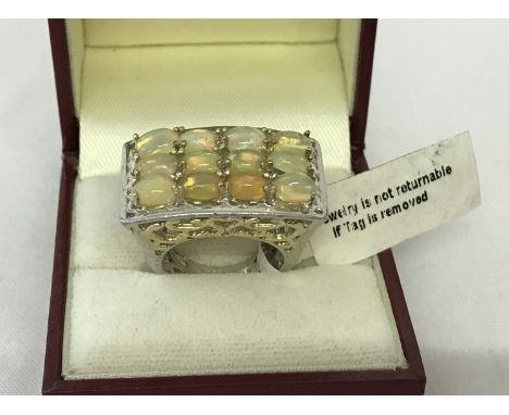 A silver dress ring by TGC with gilt detail to mount set with 12 oval opals. Hallmarks to inside of band. Pierced work decora