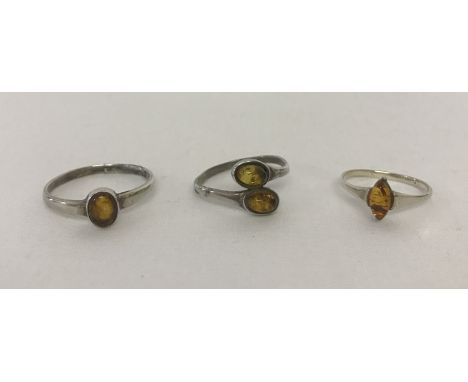 3 silver dress rings each set with amber. A ring set with an oval amber cabochon, one set with a marquise shaped amber piece 